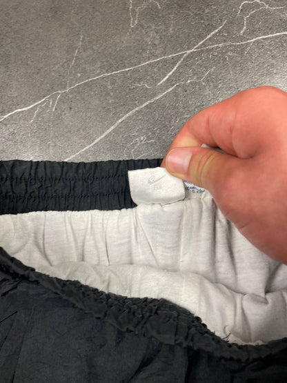Nike black track pants with elastic waistband, side pockets, and ankle snaps.