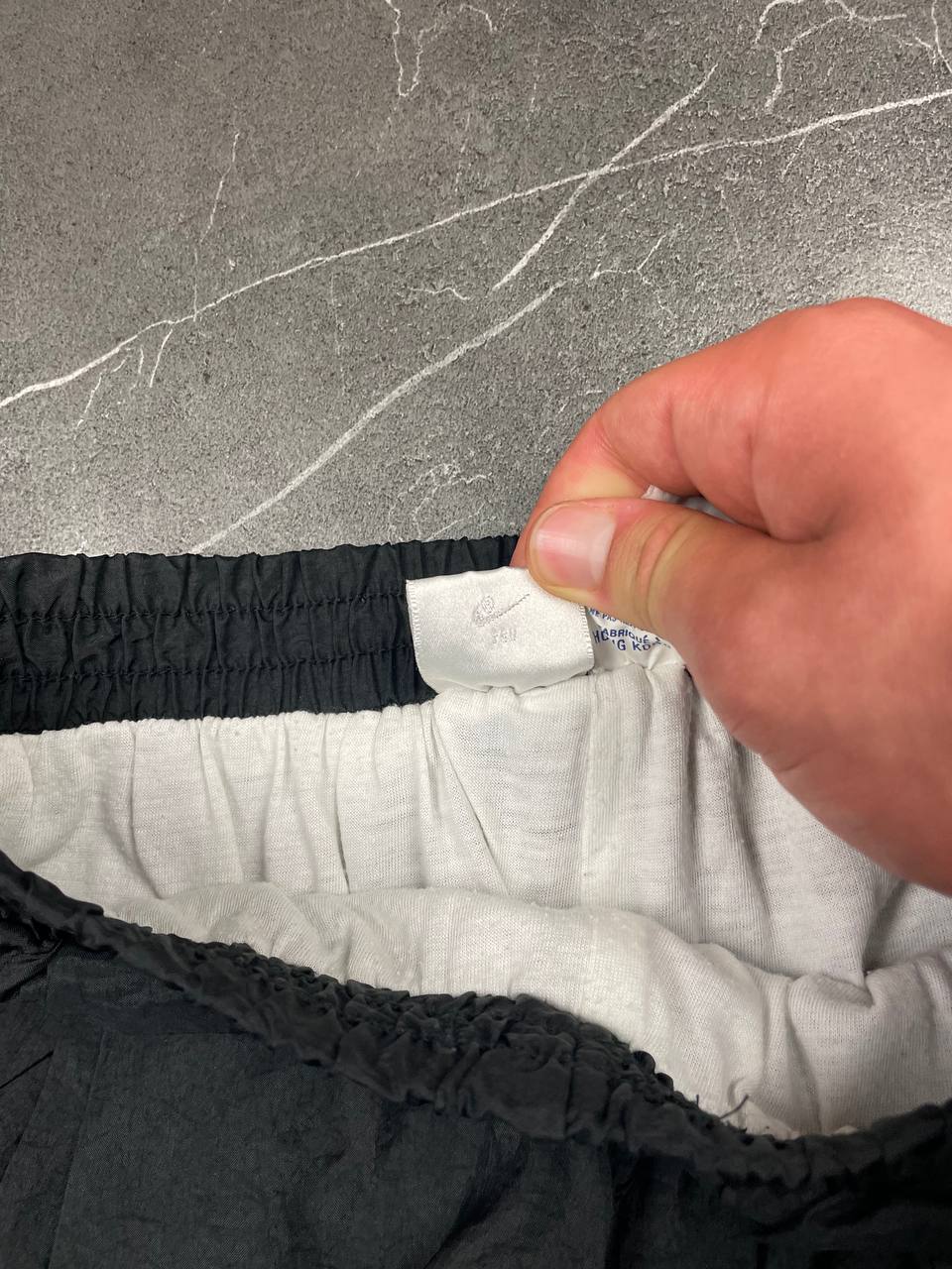 Nike black track pants with elastic waistband, side pockets, and ankle snaps.