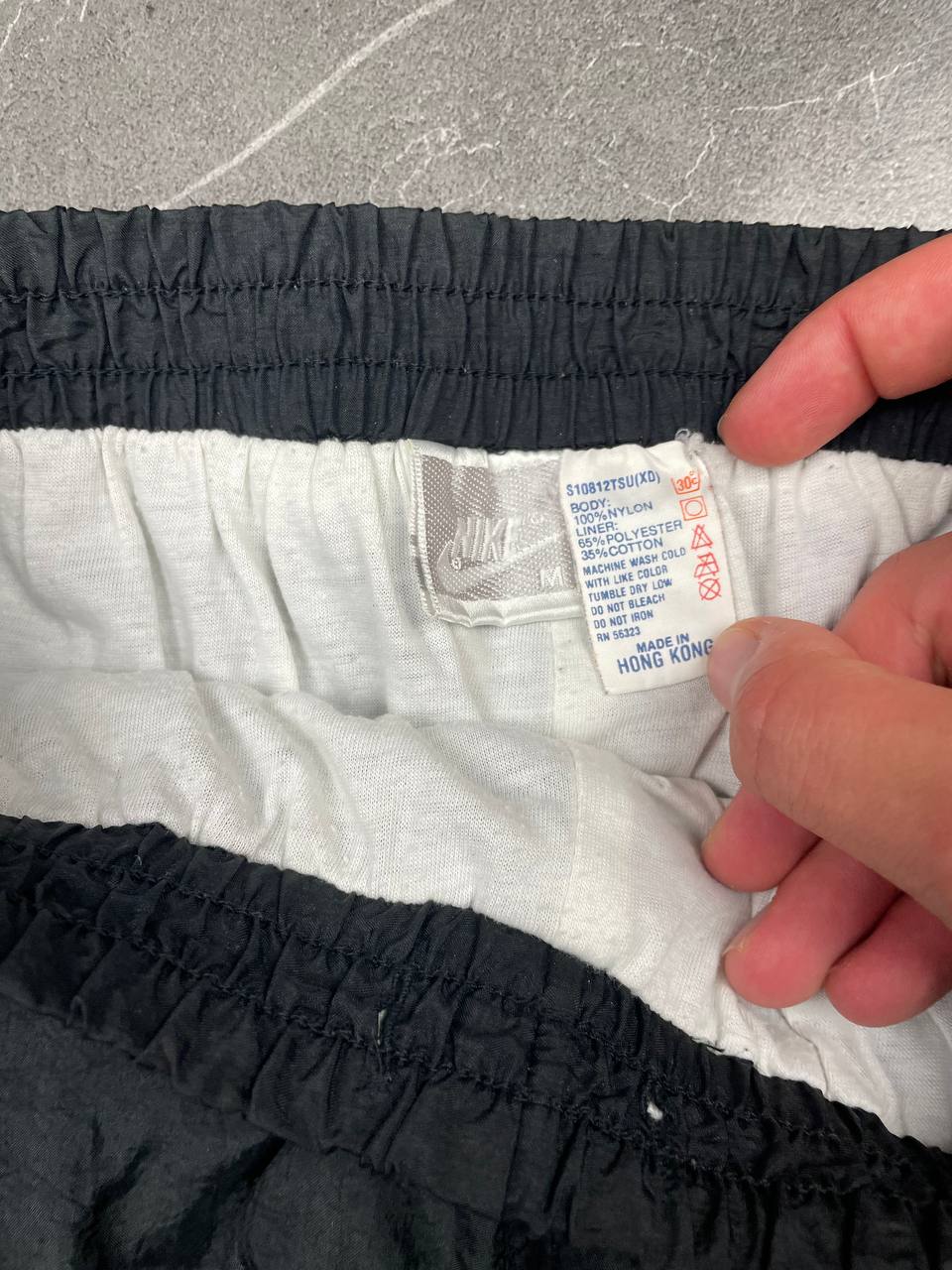Nike black track pants with elastic waistband, side pockets, and ankle snaps.