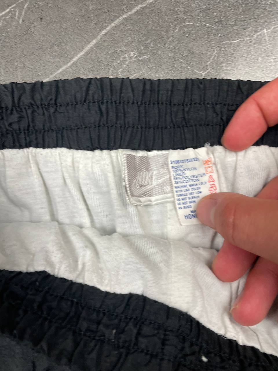 Nike black track pants with elastic waistband, side pockets, and ankle snaps.