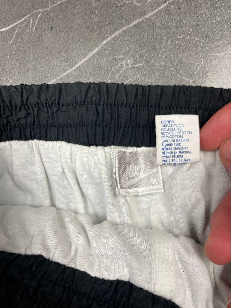 Nike black track pants with elastic waistband, side pockets, and ankle snaps.