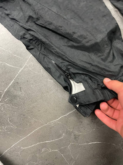 Nike black track pants with elastic waistband, side pockets, and ankle snaps.