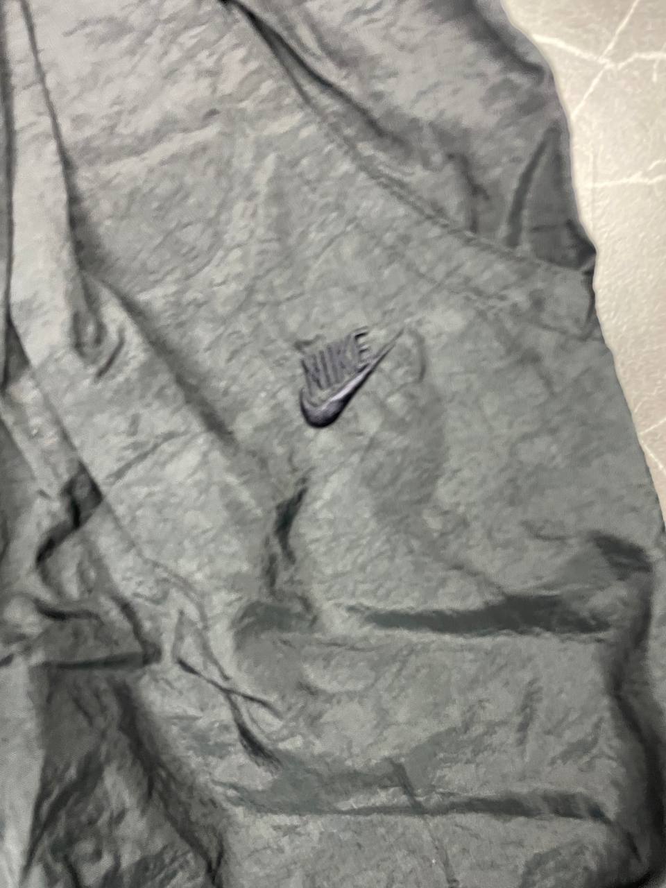 Nike black track pants with elastic waistband, side pockets, and ankle snaps.