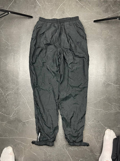 Nike black track pants with elastic waistband, side pockets, and ankle snaps.