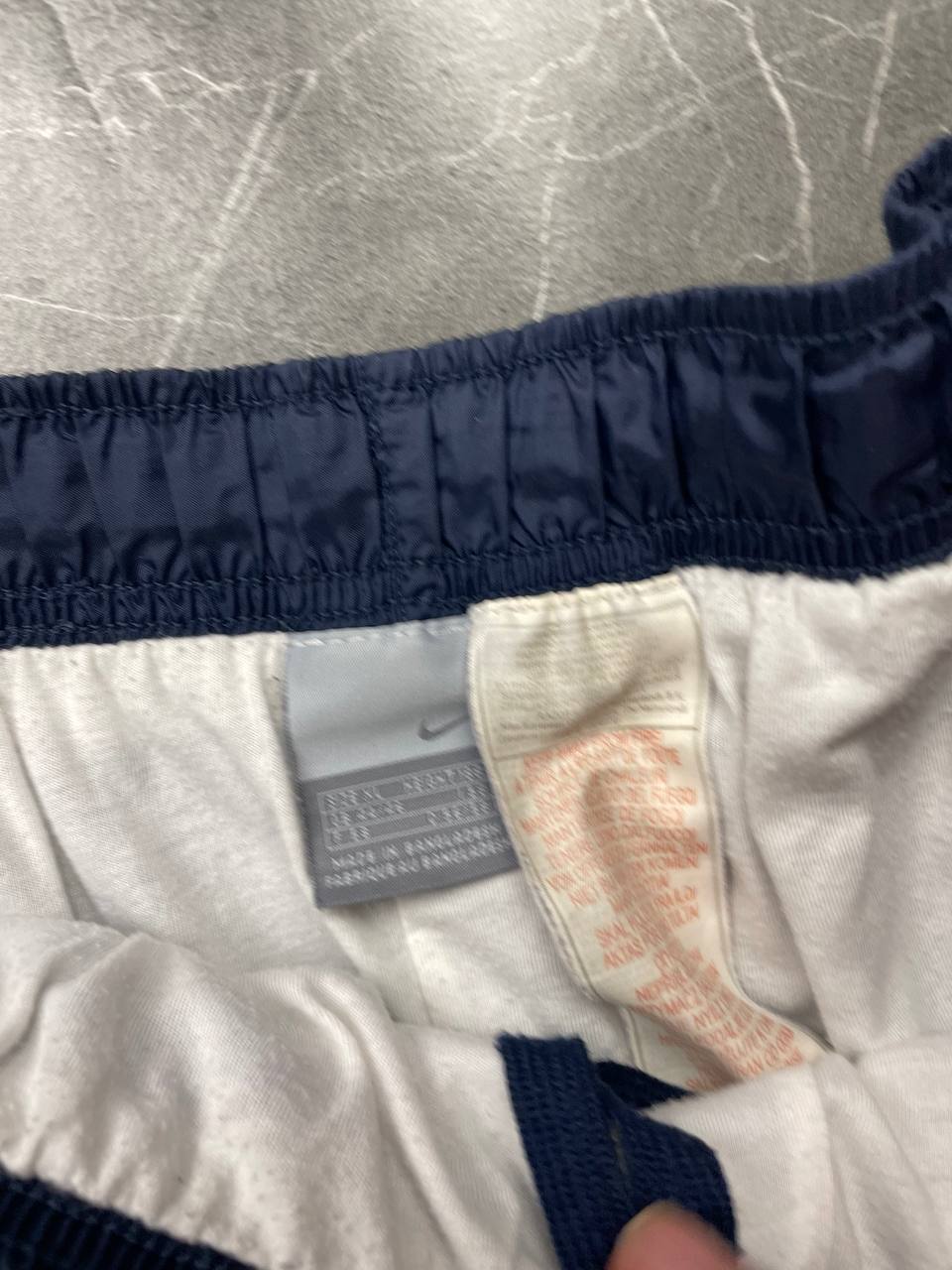 Nike red tracksuit jacket with white piping and navy pants with red trim.
