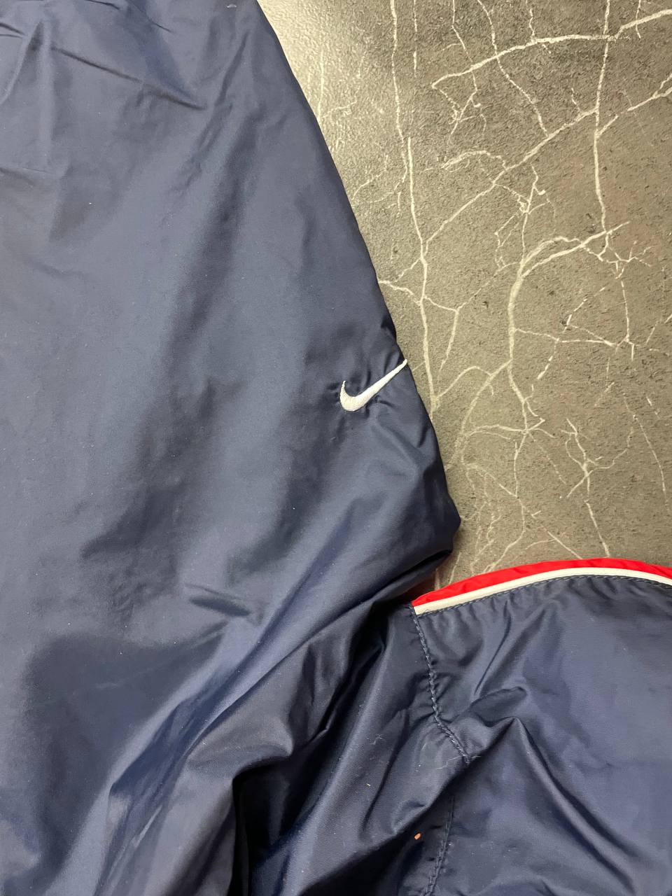 Nike red tracksuit jacket with white piping and navy pants with red trim.