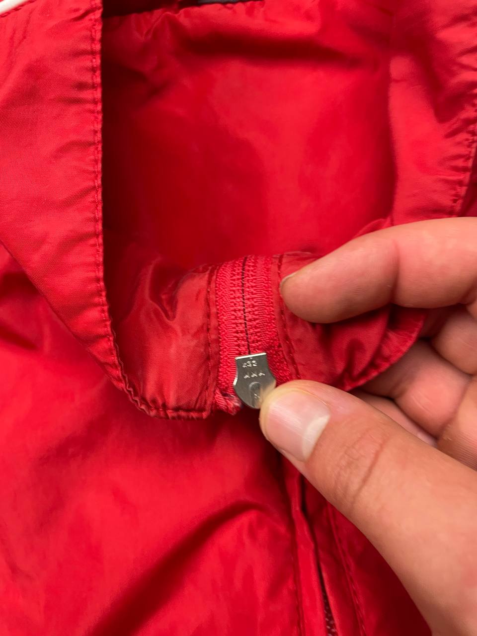 Nike red tracksuit jacket with white piping and navy pants with red trim.