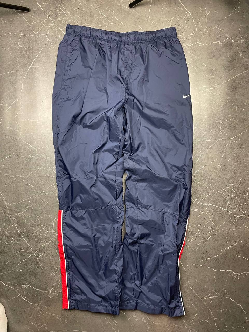 Nike red tracksuit jacket with white piping and navy pants with red trim.