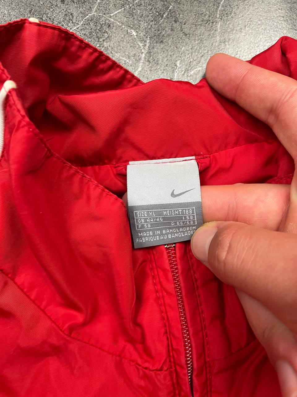 Nike red tracksuit jacket with white piping and navy pants with red trim.