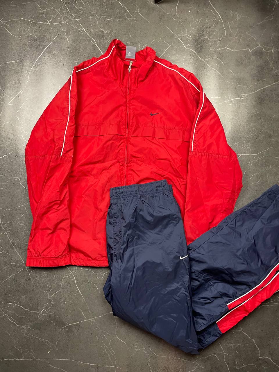 Nike red tracksuit jacket with white piping and navy pants with red trim.