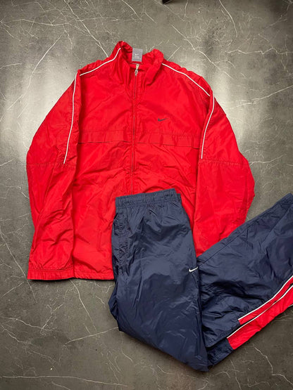 Nike red tracksuit jacket with white piping and navy pants with red trim.