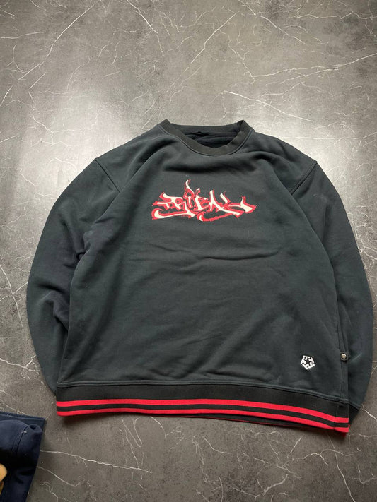 Vintage black crewneck sweatshirt with red and white embroidered logo and striped hem.
