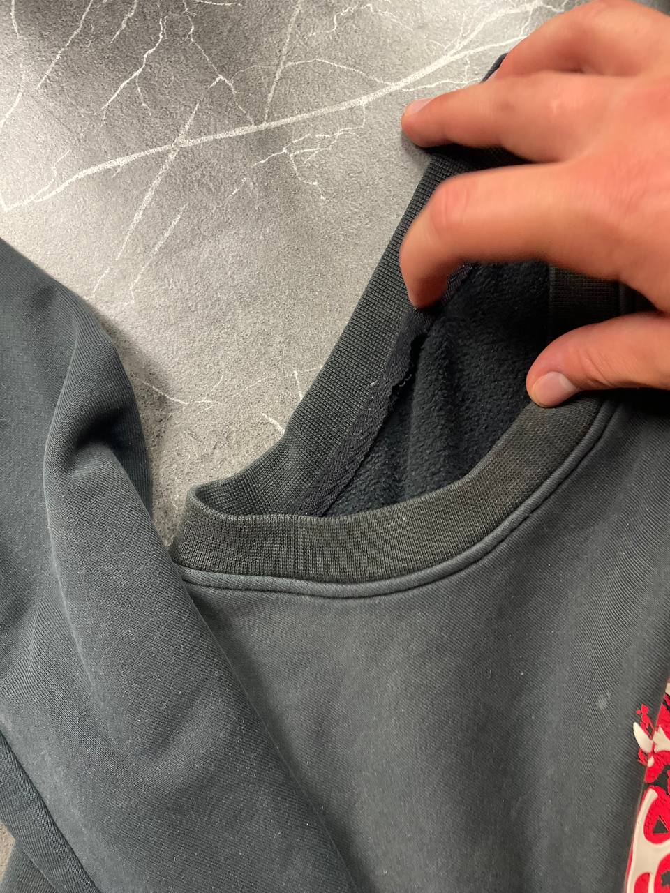 Vintage black crewneck sweatshirt with red and white embroidered logo and striped hem.
