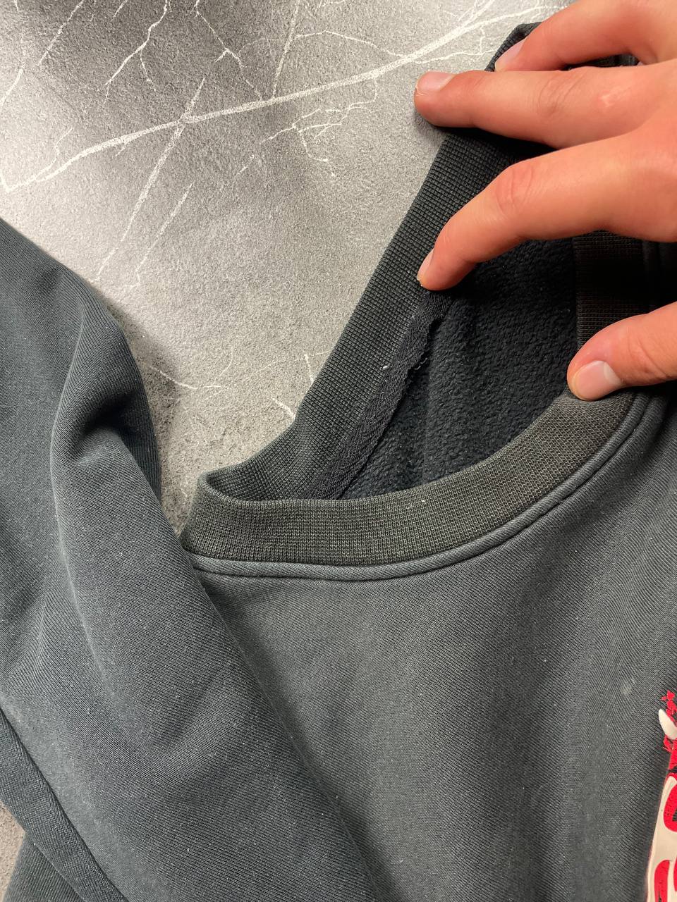Vintage black crewneck sweatshirt with red and white embroidered logo and striped hem.