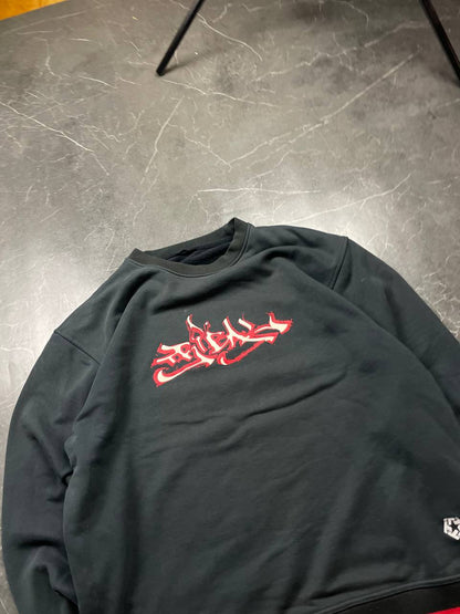 Vintage black crewneck sweatshirt with red and white embroidered logo and striped hem.