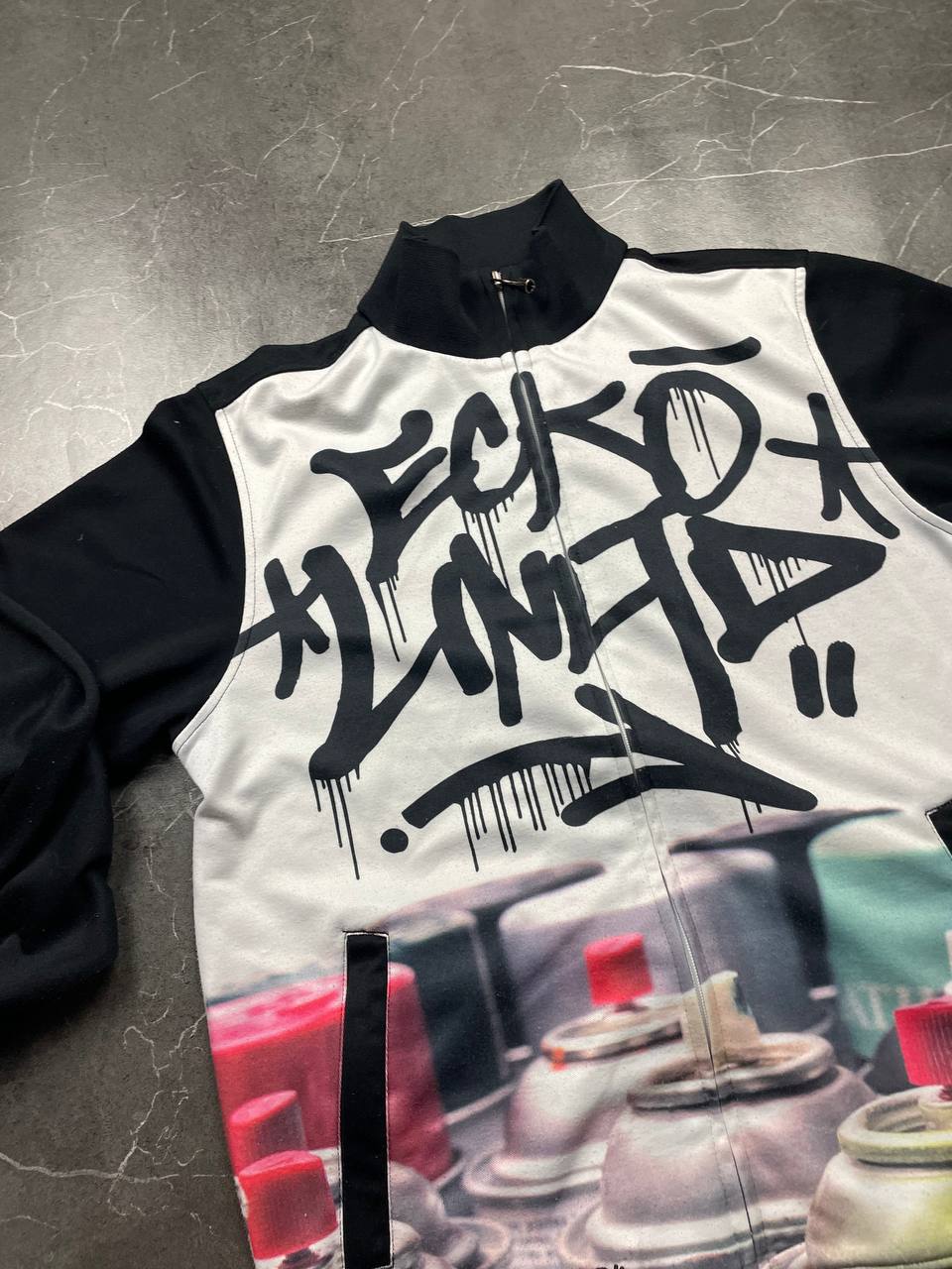 Ecko Unltd black zip-up jacket with graffiti print and spray paint can details.