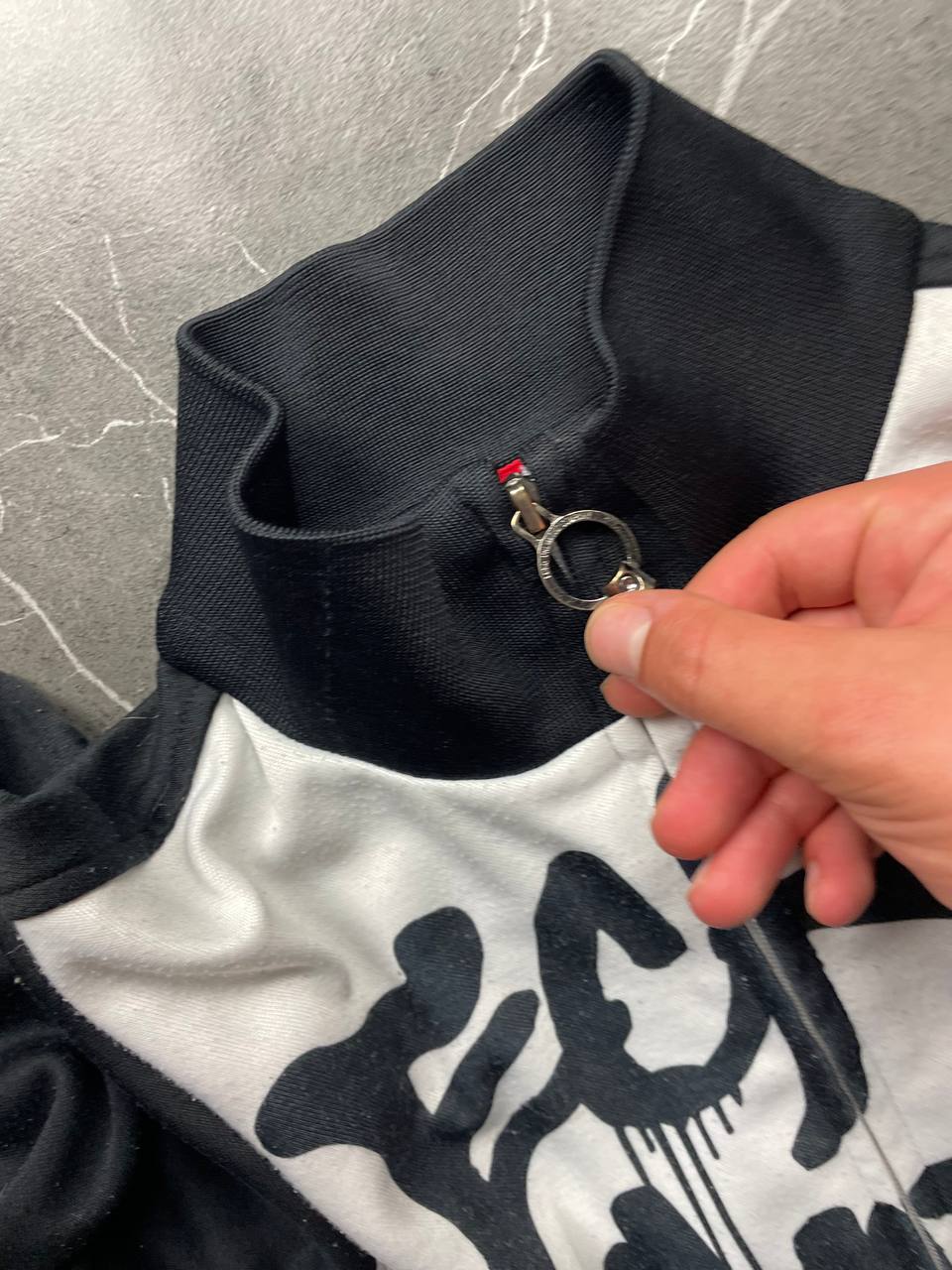 Ecko Unltd black zip-up jacket with graffiti print and spray paint can details.