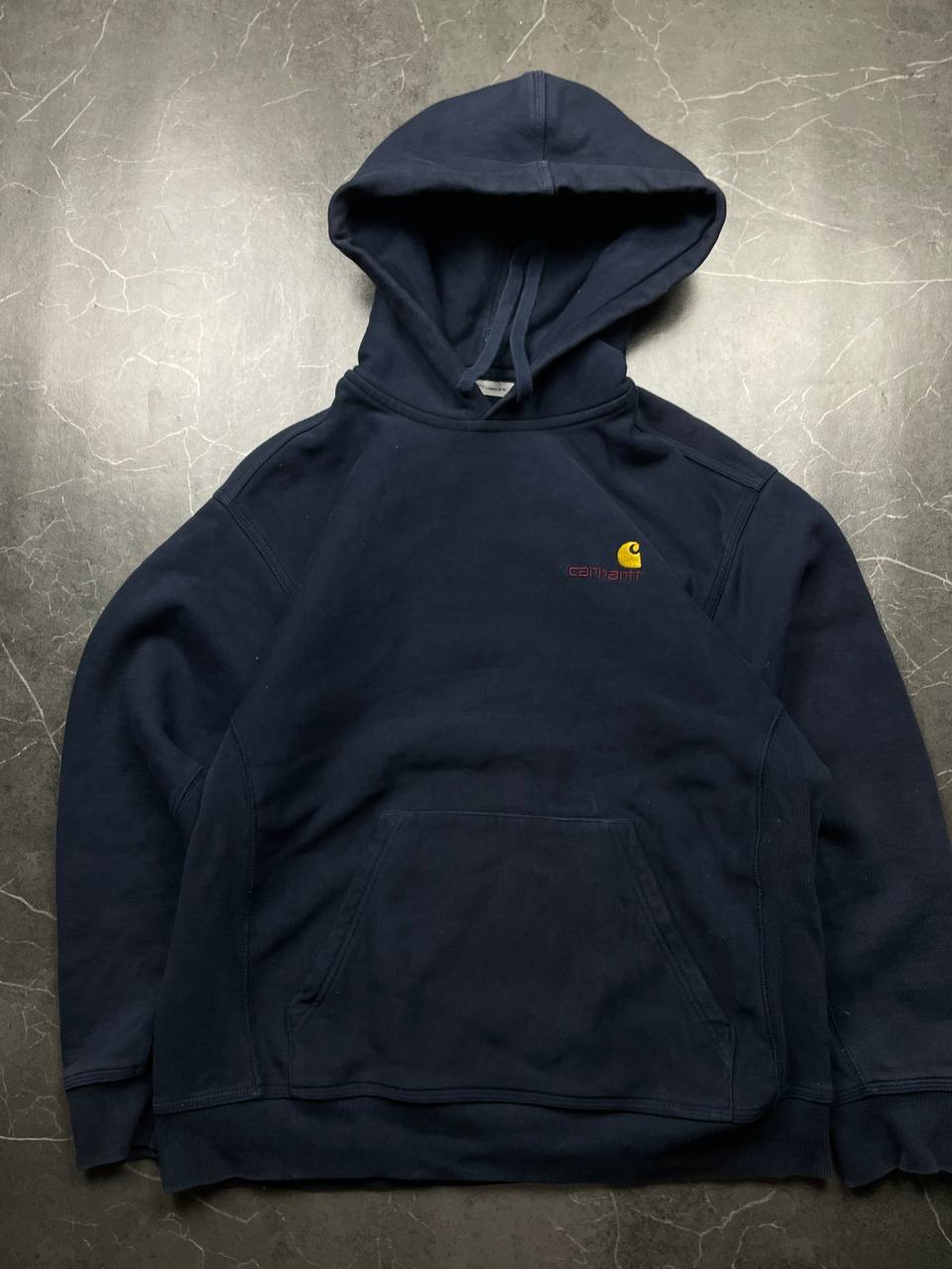 Carhartt navy hooded sweatshirt with American script logo on front left chest.