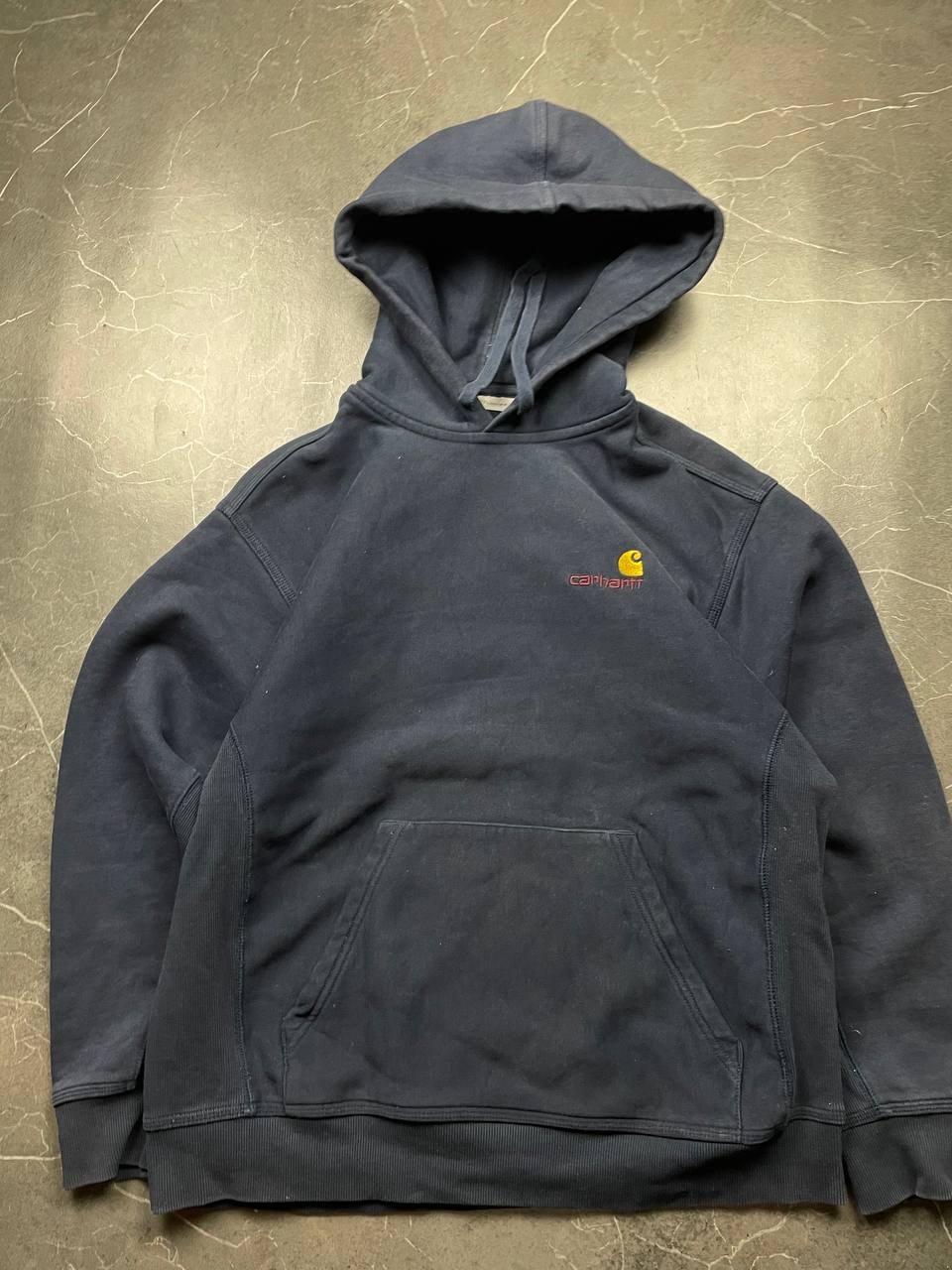 Carhartt navy hooded sweatshirt with American script logo on front left chest.