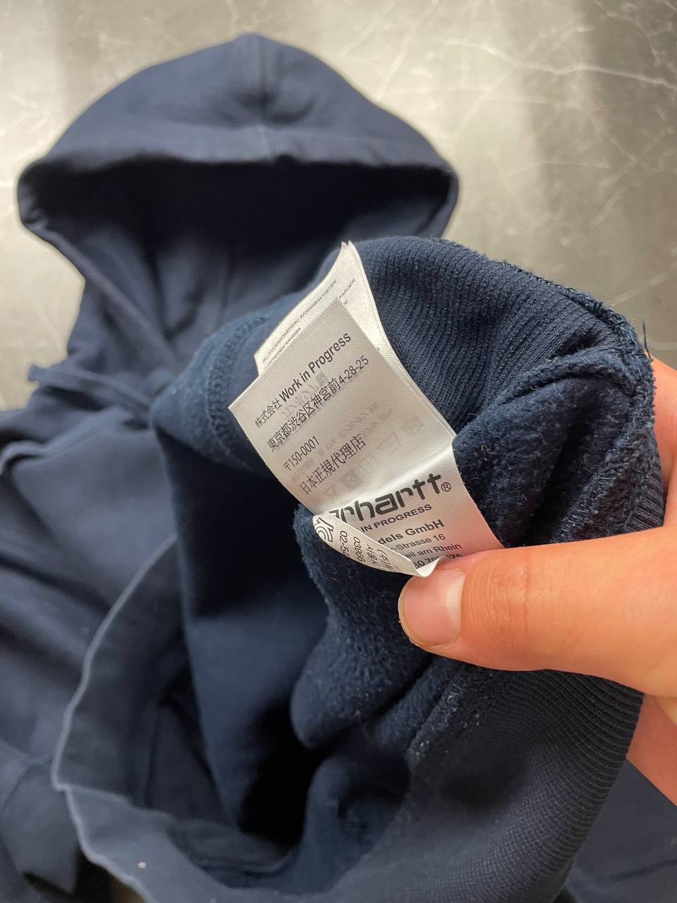 Carhartt navy hooded sweatshirt with American script logo on front left chest.