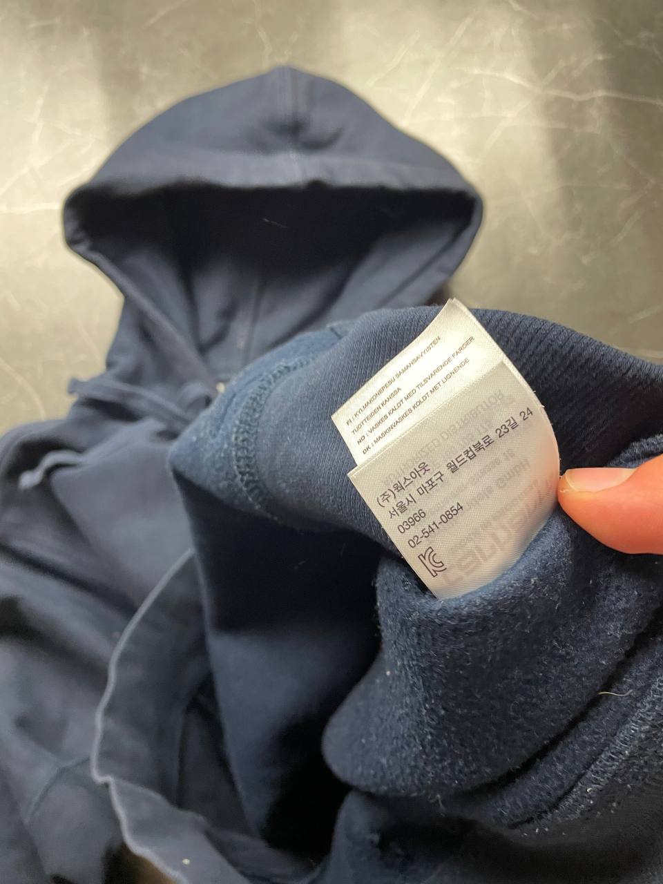 Carhartt navy hooded sweatshirt with American script logo on front left chest.