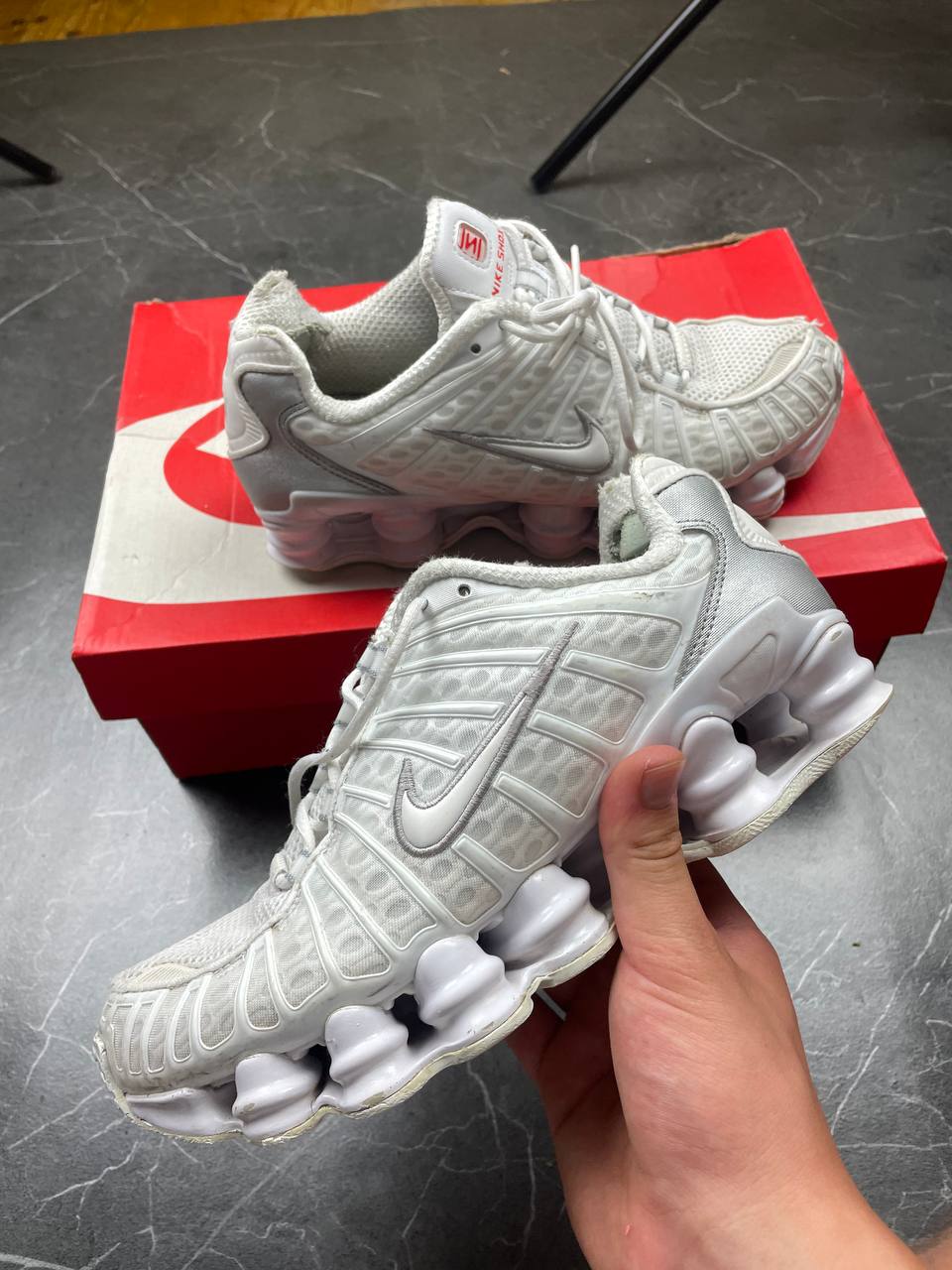 Nike silver and white running shoes with mesh upper and visible Shox cushioning columns.