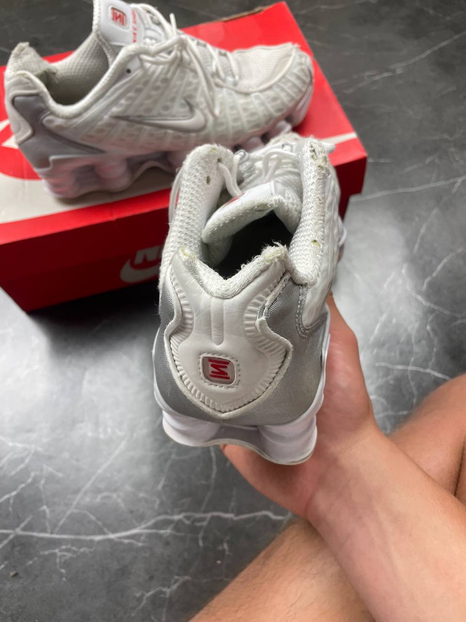 Nike silver and white running shoes with mesh upper and visible Shox cushioning columns.