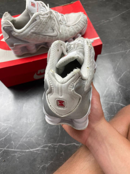 Nike silver and white running shoes with mesh upper and visible Shox cushioning columns.