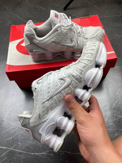 Nike silver and white running shoes with mesh upper and visible Shox cushioning columns.