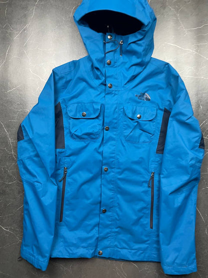 The North Face blue waterproof jacket with black accent panels and adjustable hood.