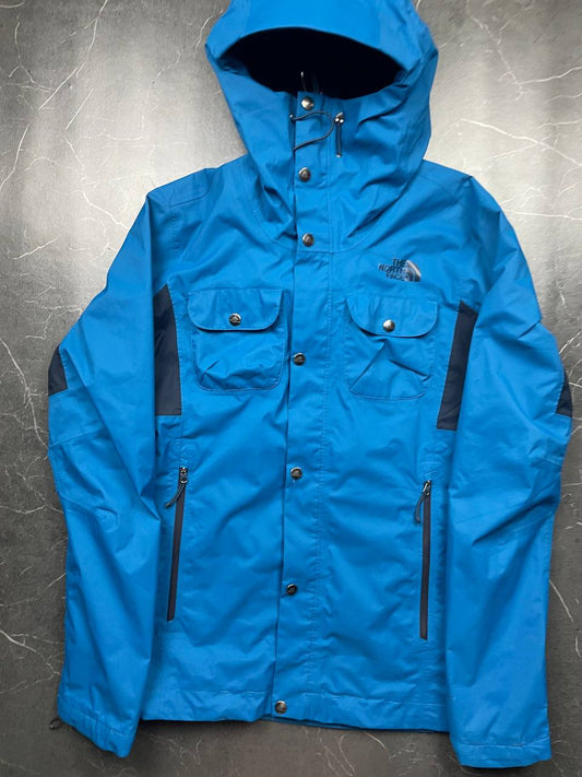 The North Face blue waterproof jacket with black accent panels and adjustable hood.