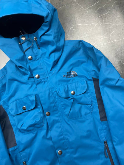 The North Face blue waterproof jacket with black accent panels and adjustable hood.