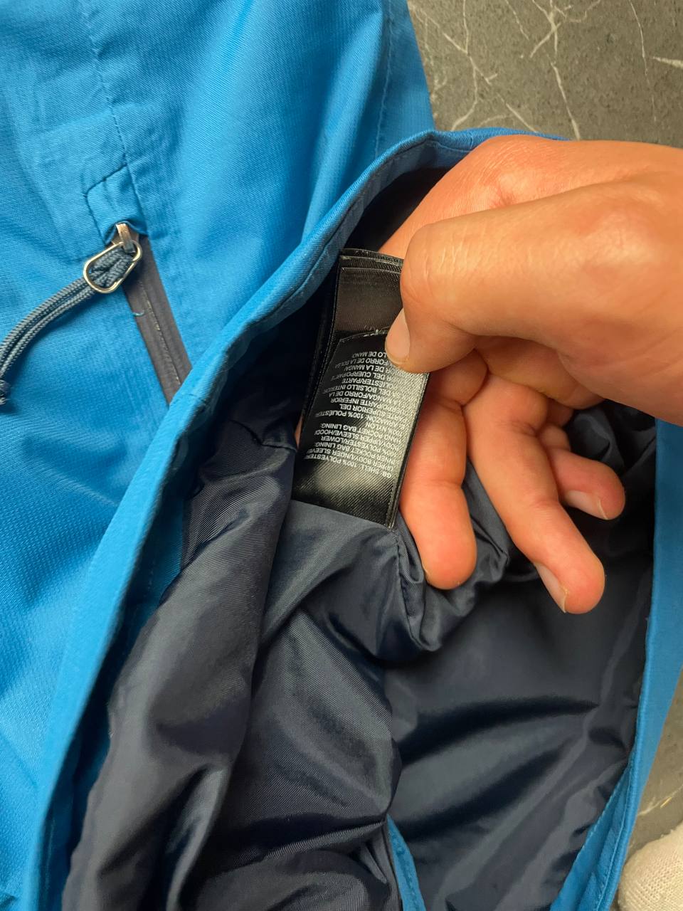 The North Face blue waterproof jacket with black accent panels and adjustable hood.