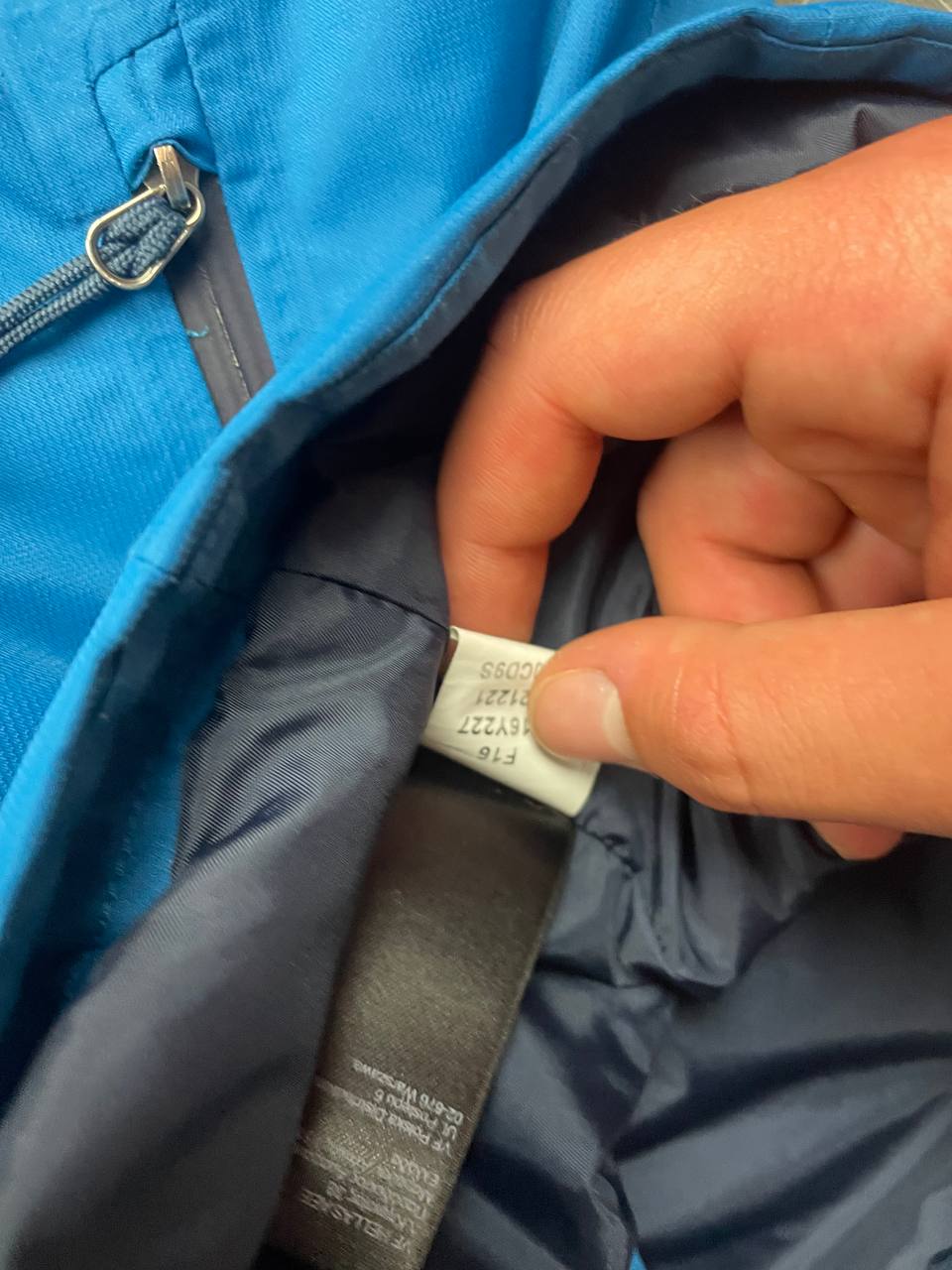 The North Face blue waterproof jacket with black accent panels and adjustable hood.