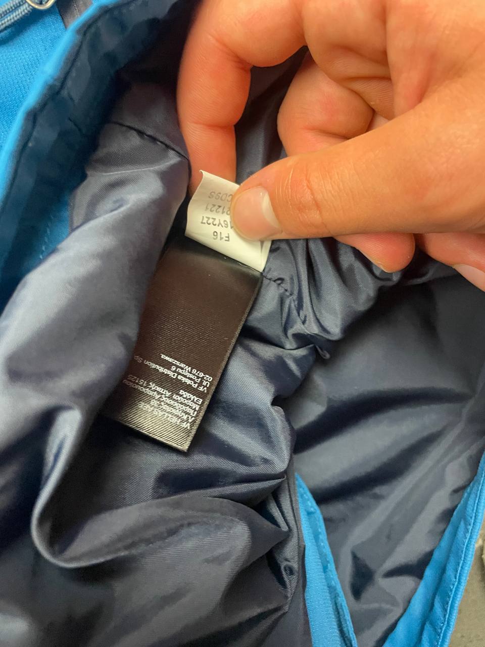 The North Face blue waterproof jacket with black accent panels and adjustable hood.