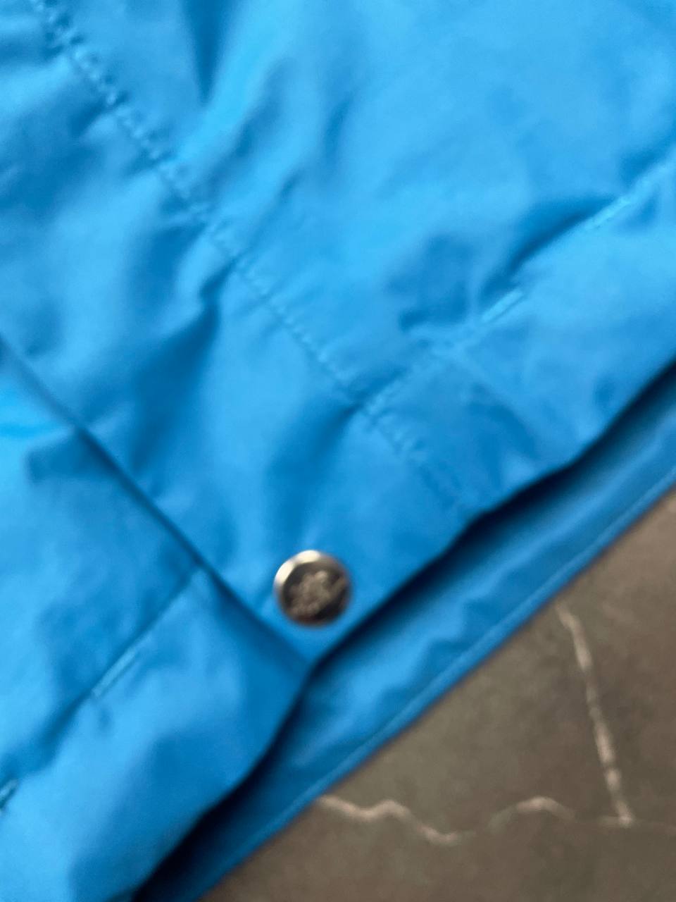 The North Face blue waterproof jacket with black accent panels and adjustable hood.