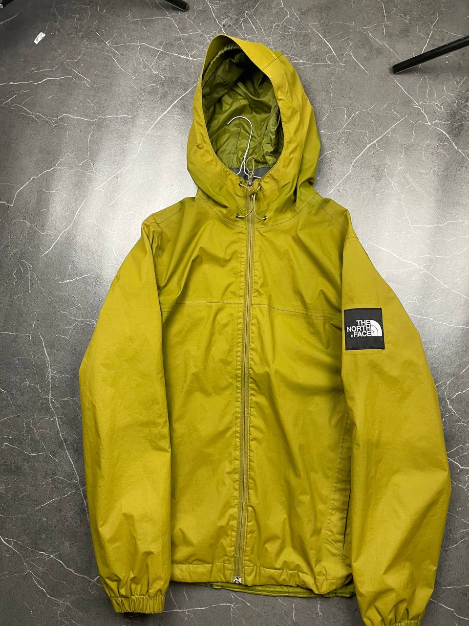The North Face green hooded windbreaker jacket with branded patch and full zip front.