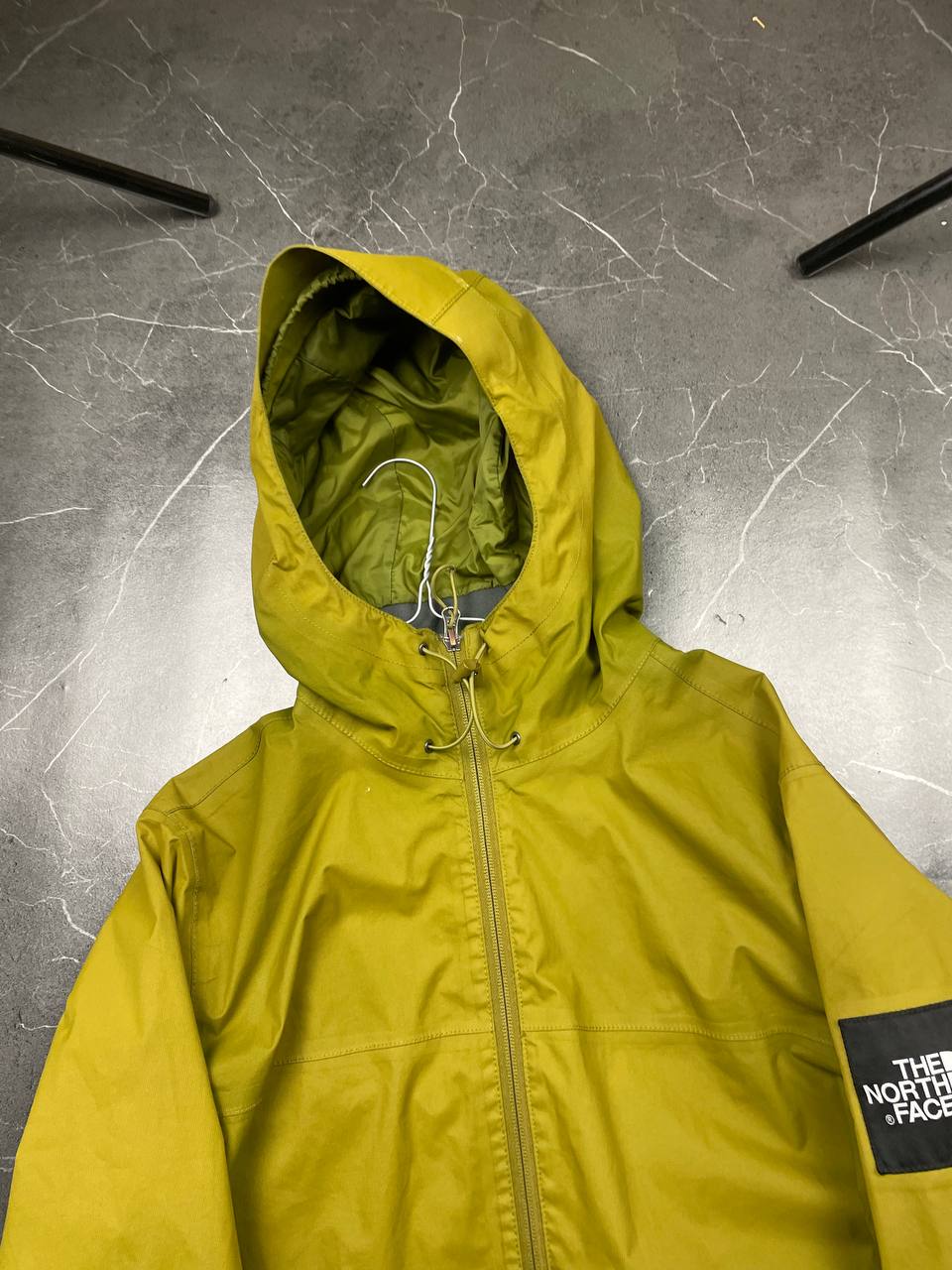 The North Face green hooded windbreaker jacket with branded patch and full zip front.