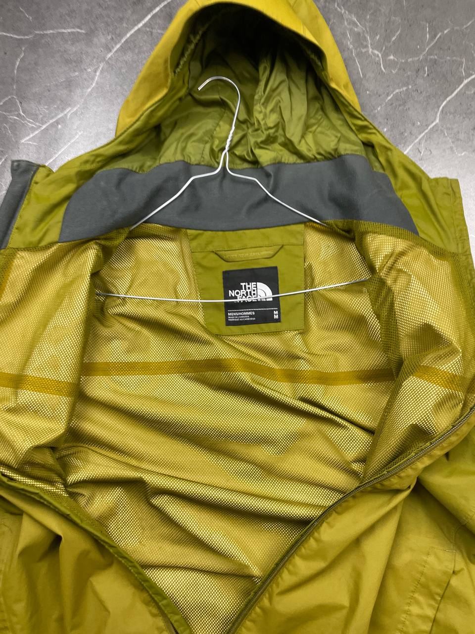 The North Face green hooded windbreaker jacket with branded patch and full zip front.