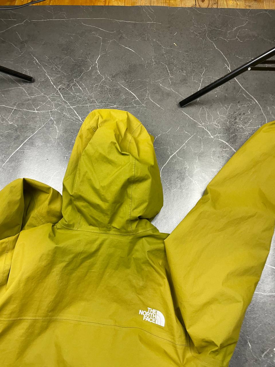 The North Face green hooded windbreaker jacket with branded patch and full zip front.