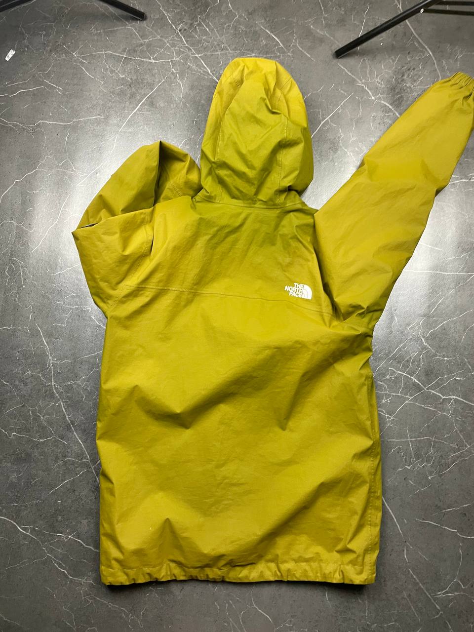 The North Face green hooded windbreaker jacket with branded patch and full zip front.