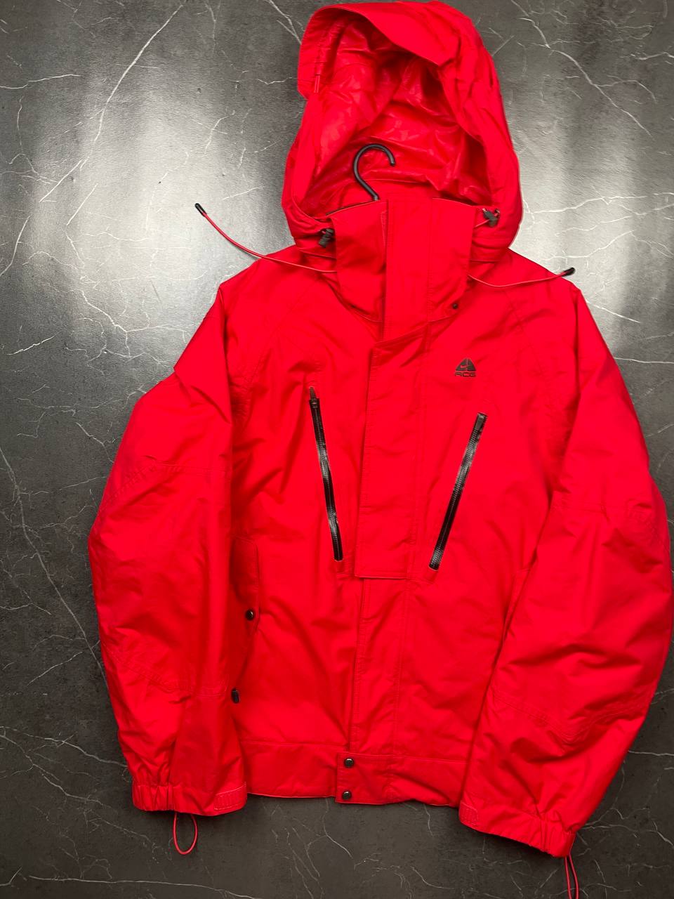 Nike red hooded jacket with waterproof zippers and adjustable hood, 100% polyester.