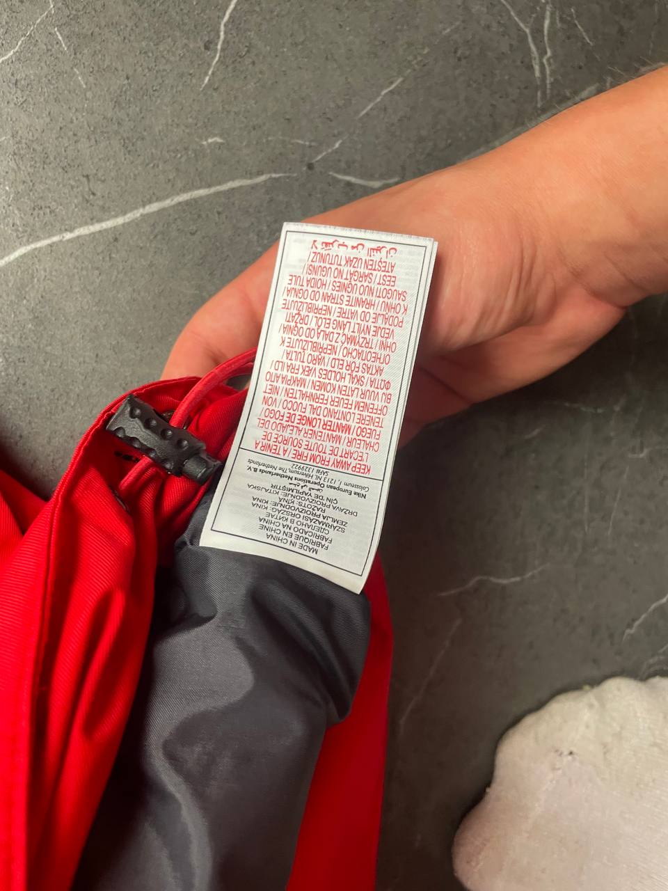 Nike red hooded jacket with waterproof zippers and adjustable hood, 100% polyester.
