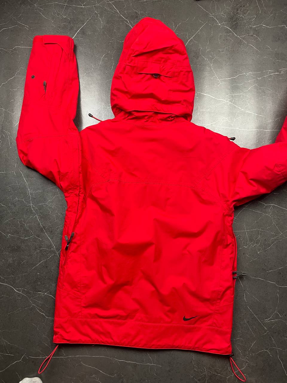 Nike red hooded jacket with waterproof zippers and adjustable hood, 100% polyester.