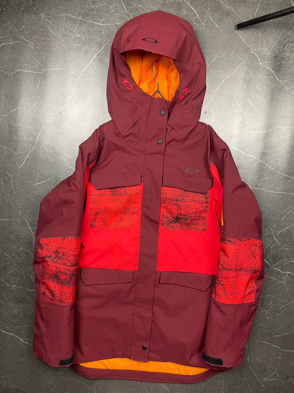Oakley burgundy and red waterproof jacket with patterned accents and adjustable hood.