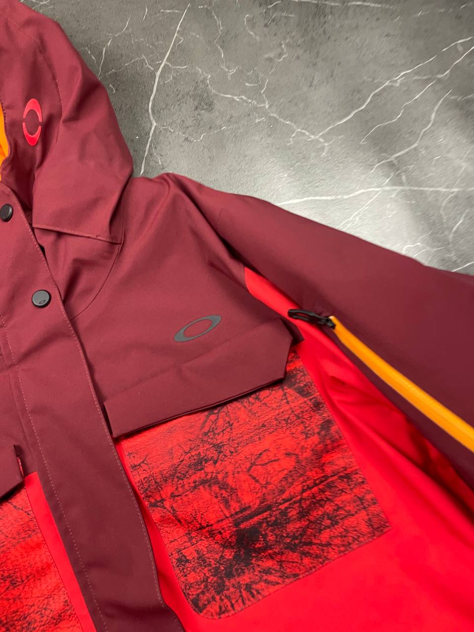 Oakley burgundy and red waterproof jacket with patterned accents and adjustable hood.