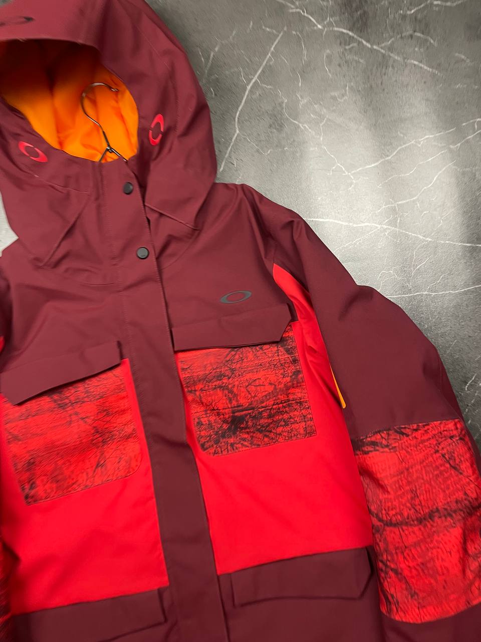 Oakley burgundy and red waterproof jacket with patterned accents and adjustable hood.