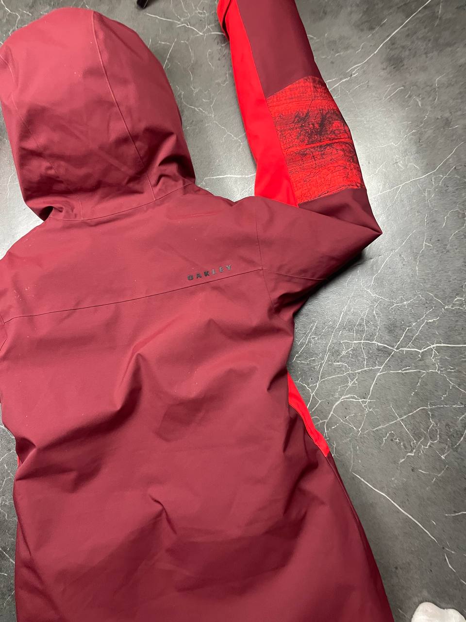 Oakley burgundy and red waterproof jacket with patterned accents and adjustable hood.