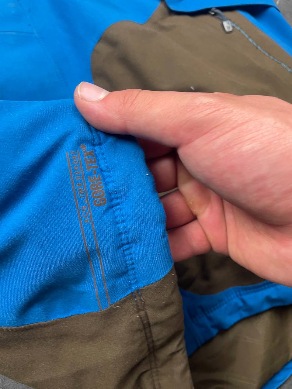 Nike ACG blue and brown waterproof jacket with Gore-Tex label and adjustable hood.