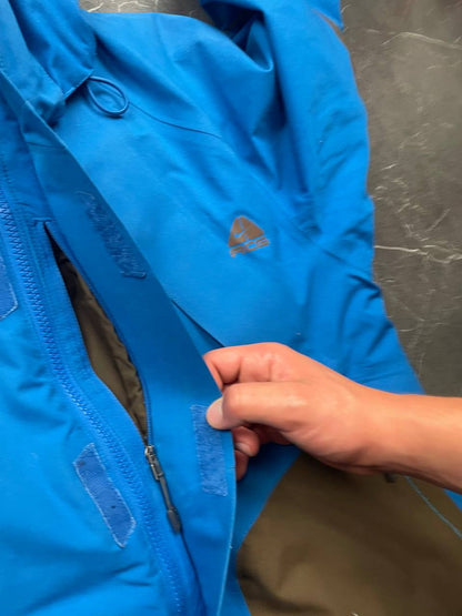 Nike ACG blue and brown waterproof jacket with Gore-Tex label and adjustable hood.